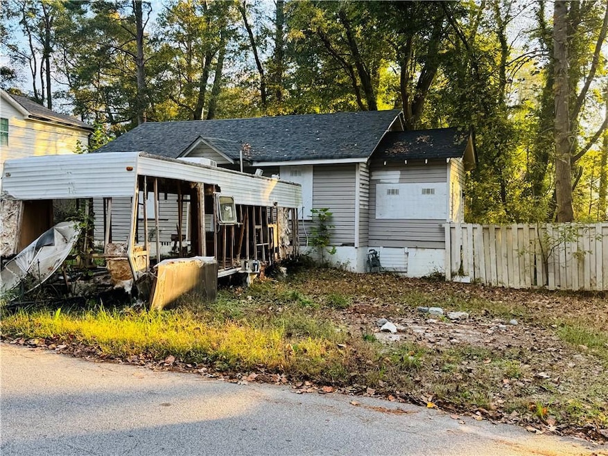 View of front facade with view of scattered trees and a shingled roof