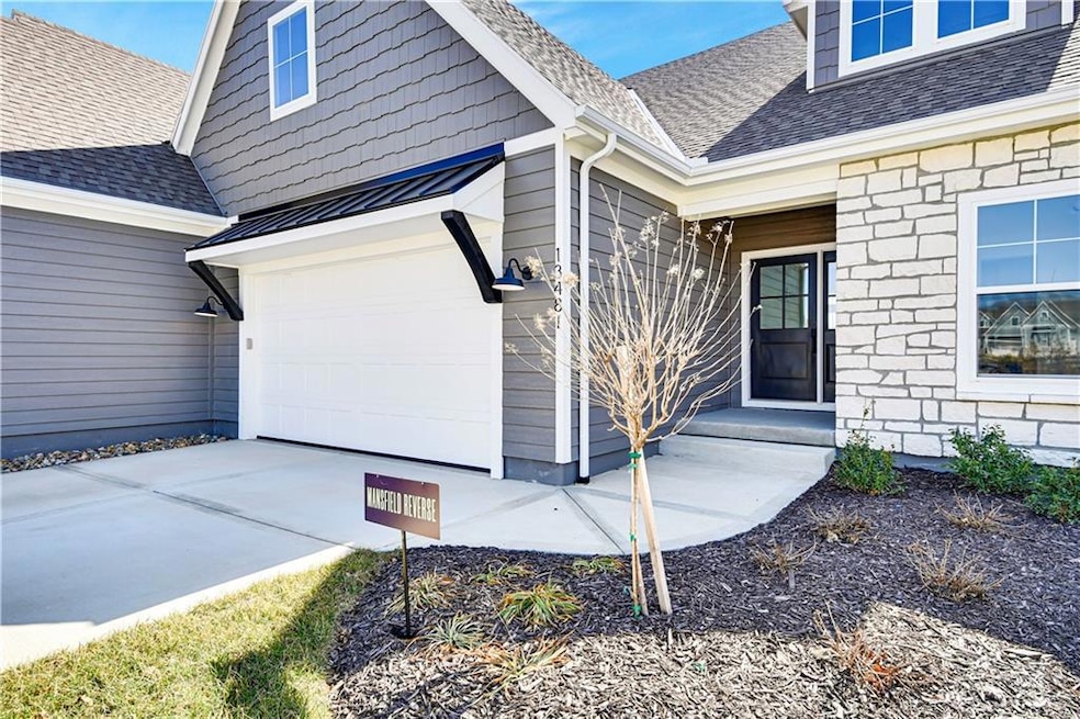 Entrance to property featuring roof with shingles, stone siding, a garage, and concrete driveway