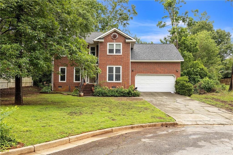View of front of property with brick siding, driveway, a front lawn, a shingled roof, and crawl space