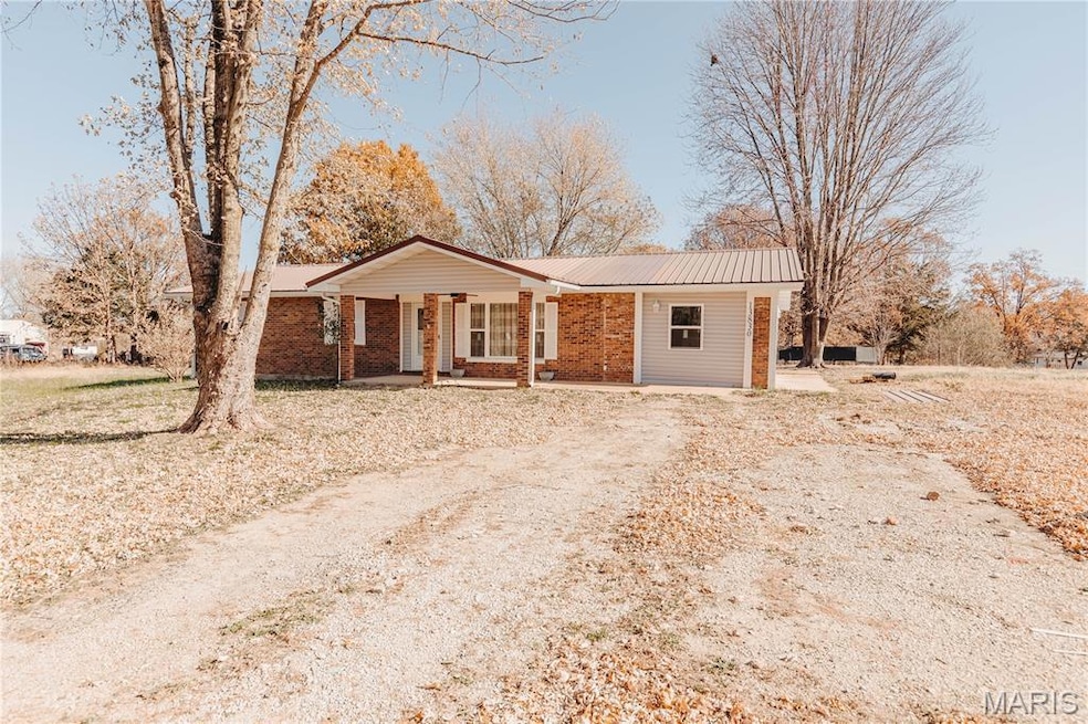 Ranch-style home featuring covered porch, a metal roof, and brick siding