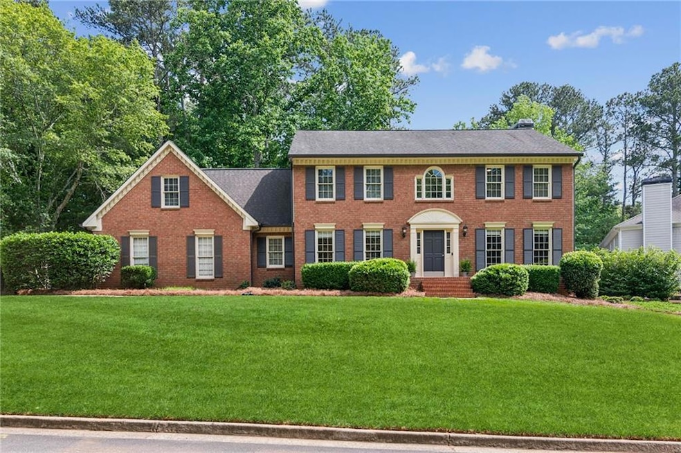 Colonial home featuring brick siding and a front yard