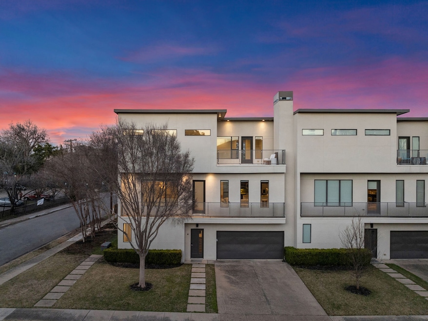Modern home featuring a balcony, stucco siding, concrete driveway, an attached garage, and a chimney