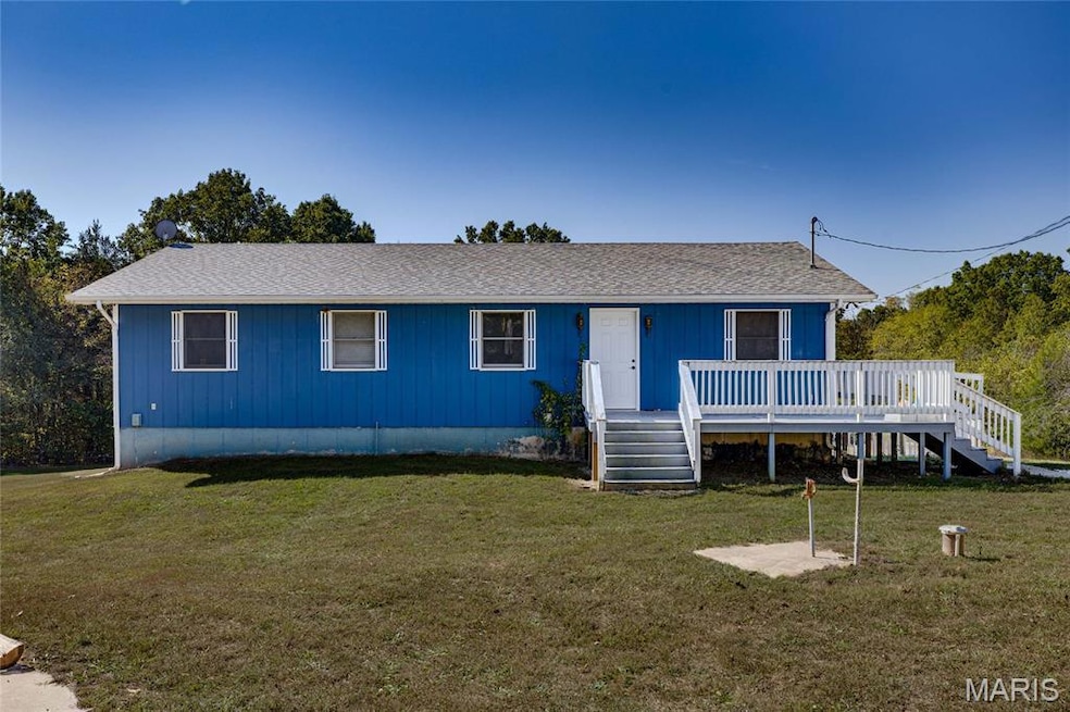 View of front of property featuring a front lawn, stairs, and roof with shingles