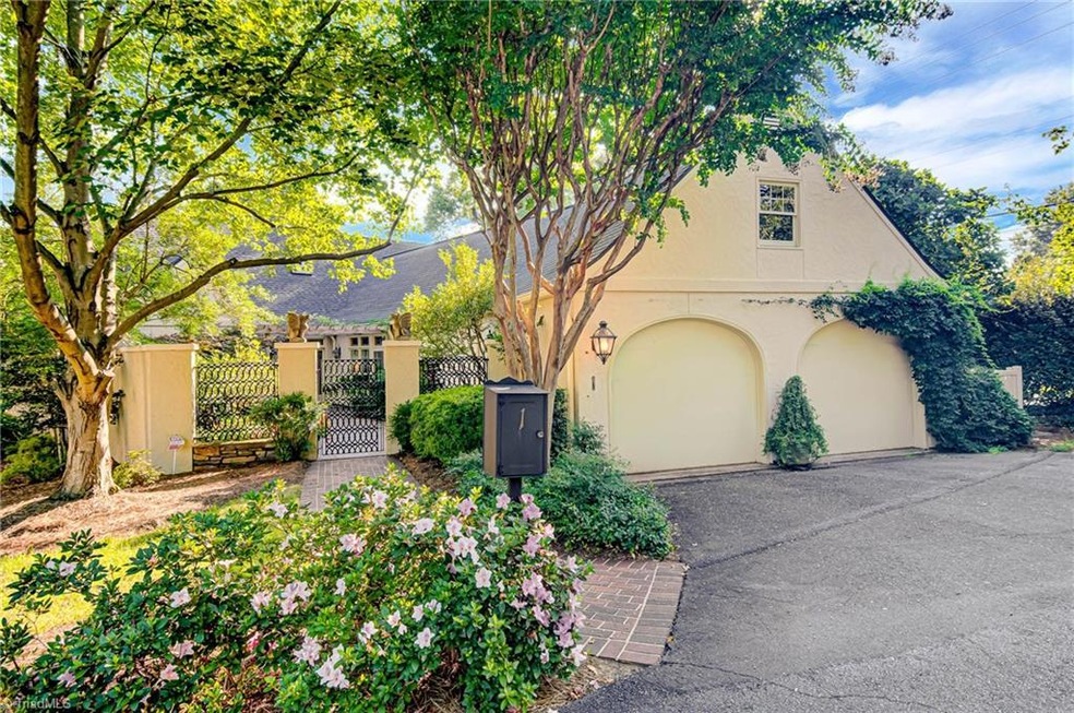 Entrance to the front courtyard through the iron gate, 2 car garage with additional outdoor parking across the driveway