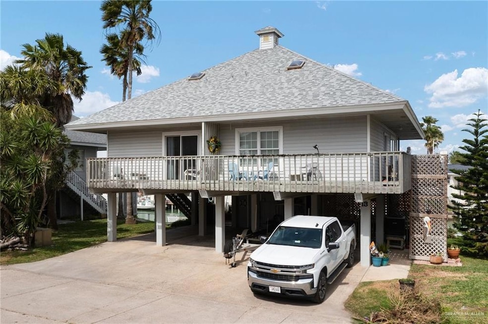 Back of property featuring a carport, stairway, roof with shingles, and driveway