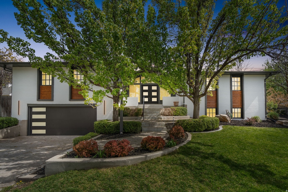 View of front of home with decorative driveway, a front yard, a garage, brick siding, and french doors