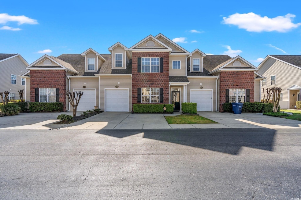 View of property featuring concrete driveway, brick siding, a garage, and a residential view