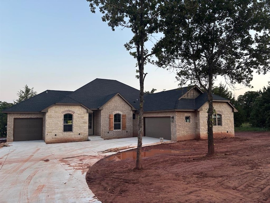 French country home featuring an attached garage, driveway, and brick siding