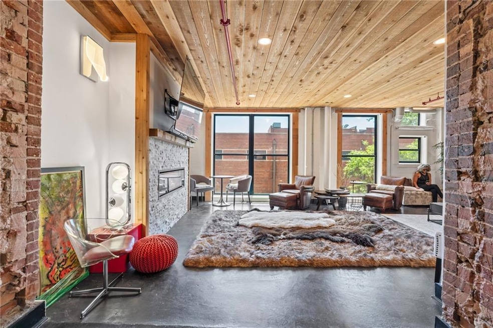 Sitting room featuring wooden ceiling, a glass covered fireplace, and concrete flooring