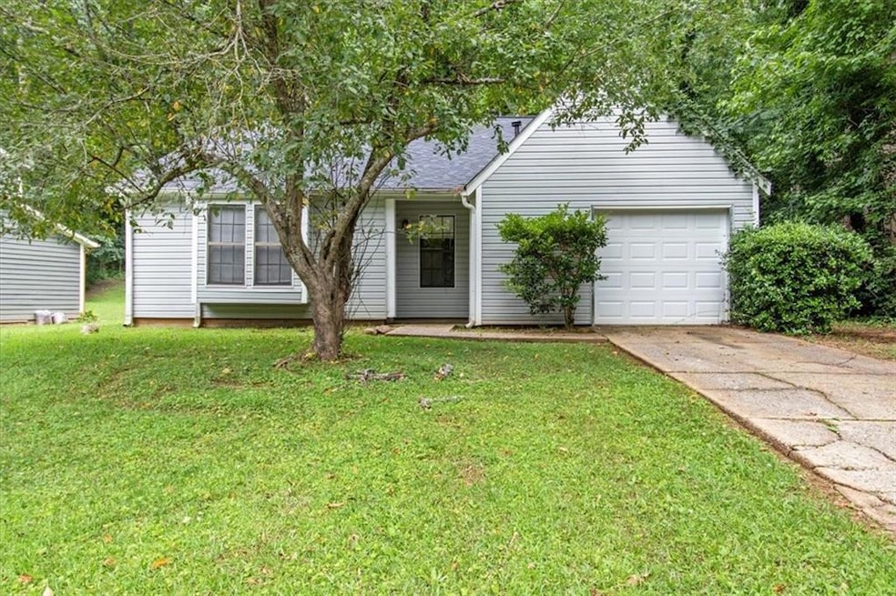 View of front of house featuring concrete driveway, a front yard, and a garage
