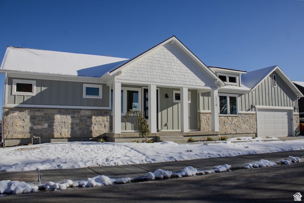 View of front of home featuring stone siding, covered porch, and board and batten siding