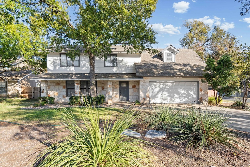 View of front of home featuring concrete driveway, stone siding, a garage, and a shingled roof