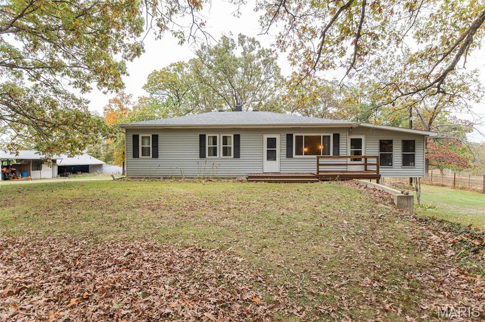 Ranch-style home featuring a front lawn and a wooden deck