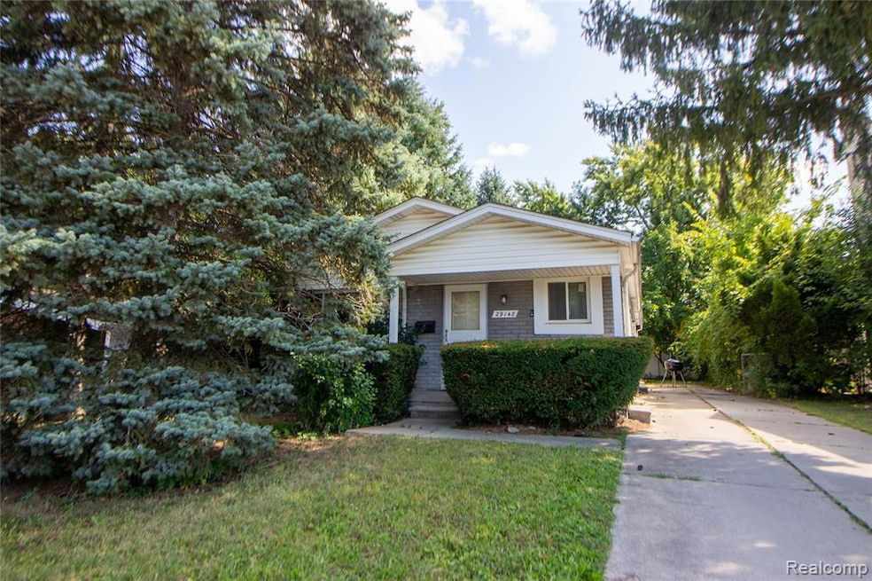 View of front of house featuring a porch, a front yard, brick siding, and driveway