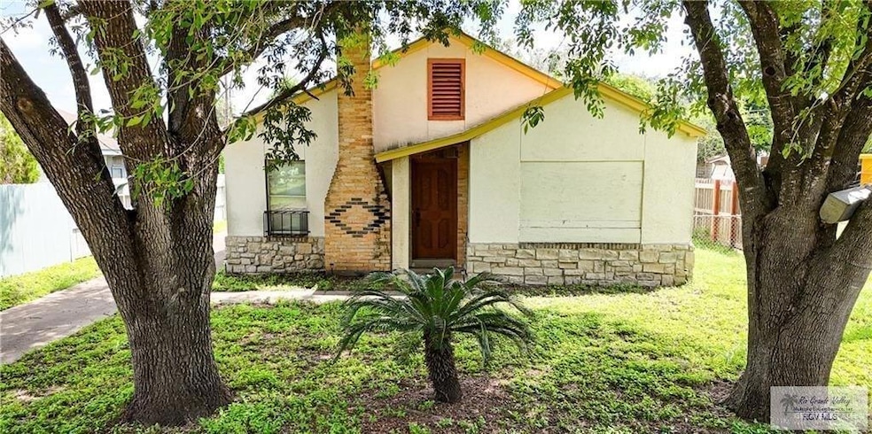 View of front facade with a front lawn, fence, stone siding, and stucco siding