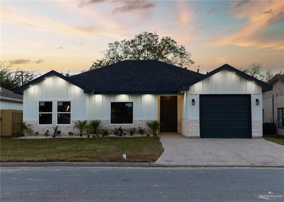 Modern farmhouse featuring stone siding, board and batten siding, a garage, and decorative driveway