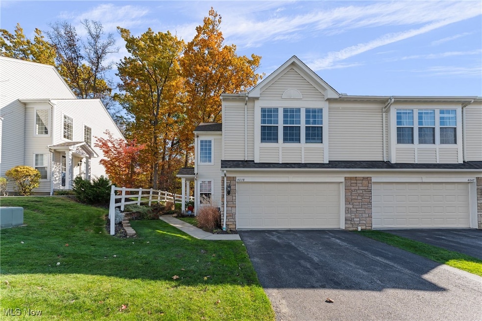 Traditional-style house featuring asphalt driveway, stone siding, and a garage