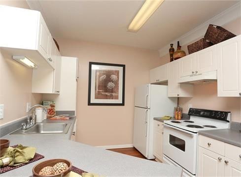 Kitchen with white cabinets, white appliances, sink, and custom exhaust hood