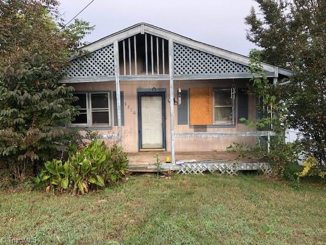 Front View - Here we can see the large front porch, one of the main entrance doors, the green grass, mature landscaping and trees.