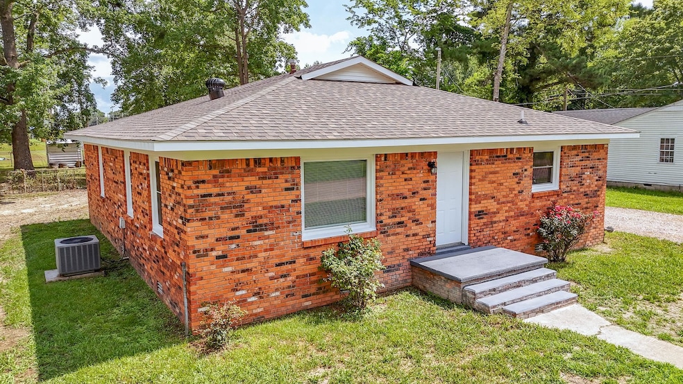View of front of property featuring roof with shingles, a front yard, and brick siding
