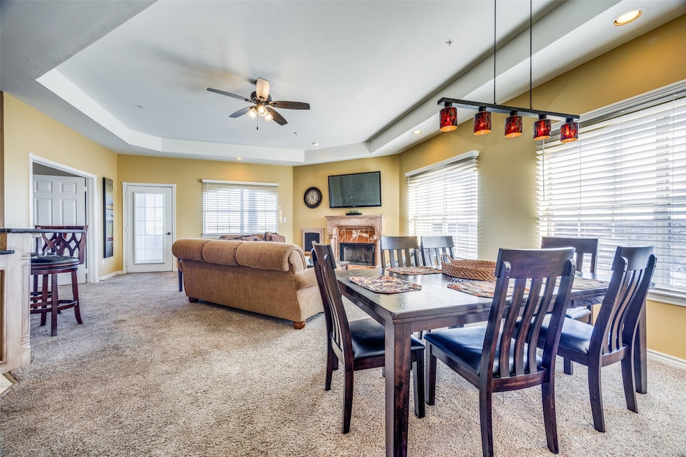 Carpeted dining area with ceiling fan and a tray ceiling