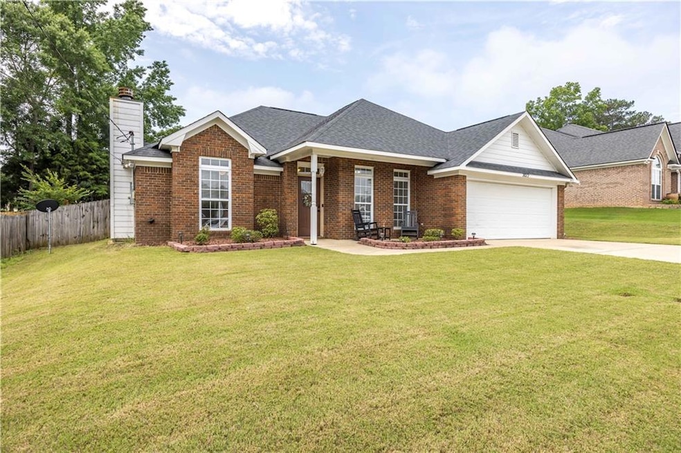 View of front of house featuring an attached garage, driveway, brick siding, a chimney, and a shingled roof