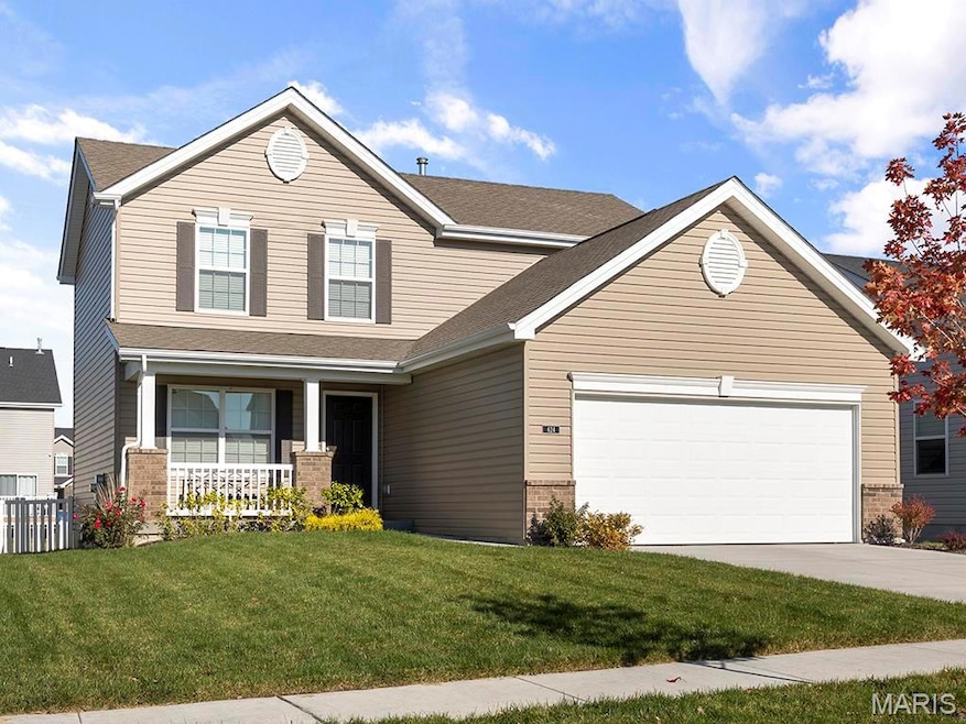 View of front of house with covered porch, a garage, and a front lawn