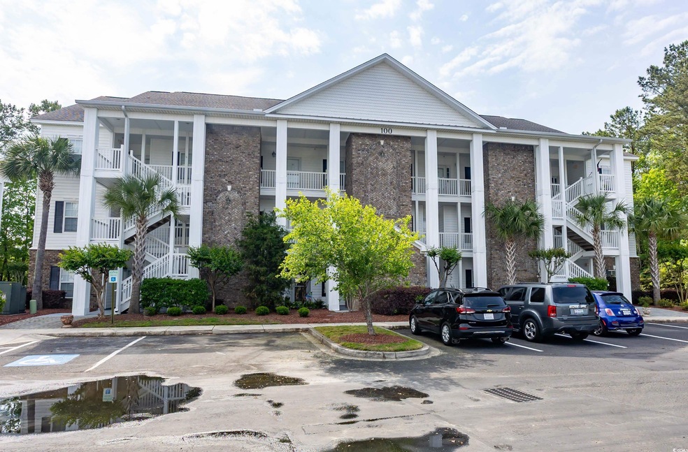 View of property with stairs and uncovered parking