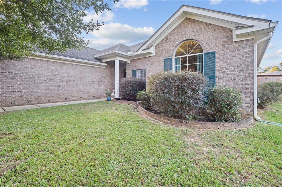 View of front facade featuring a front yard, brick siding, and roof with shingles