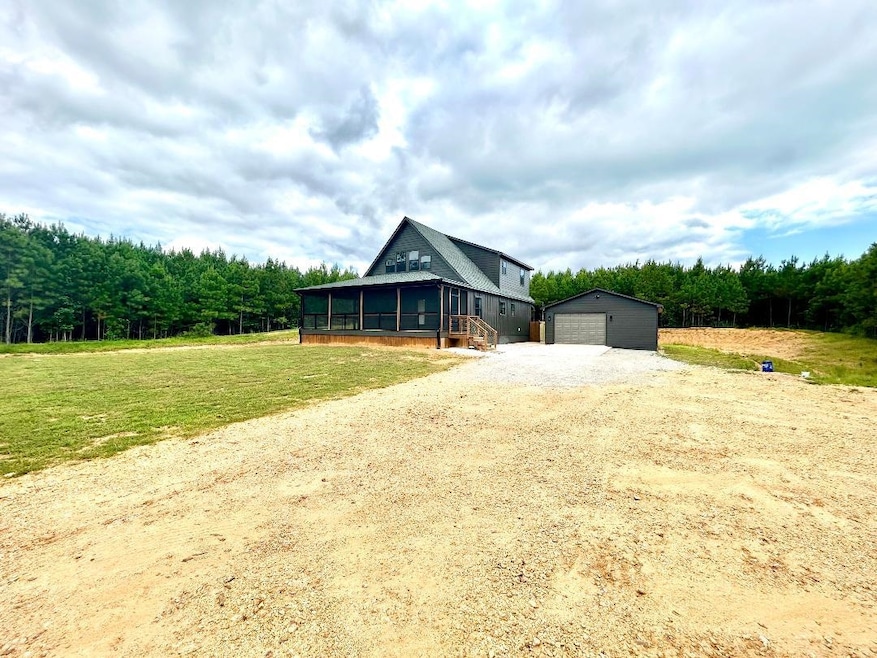 View of front of home with a sunroom, an outdoor structure, driveway, a garage, and a front lawn