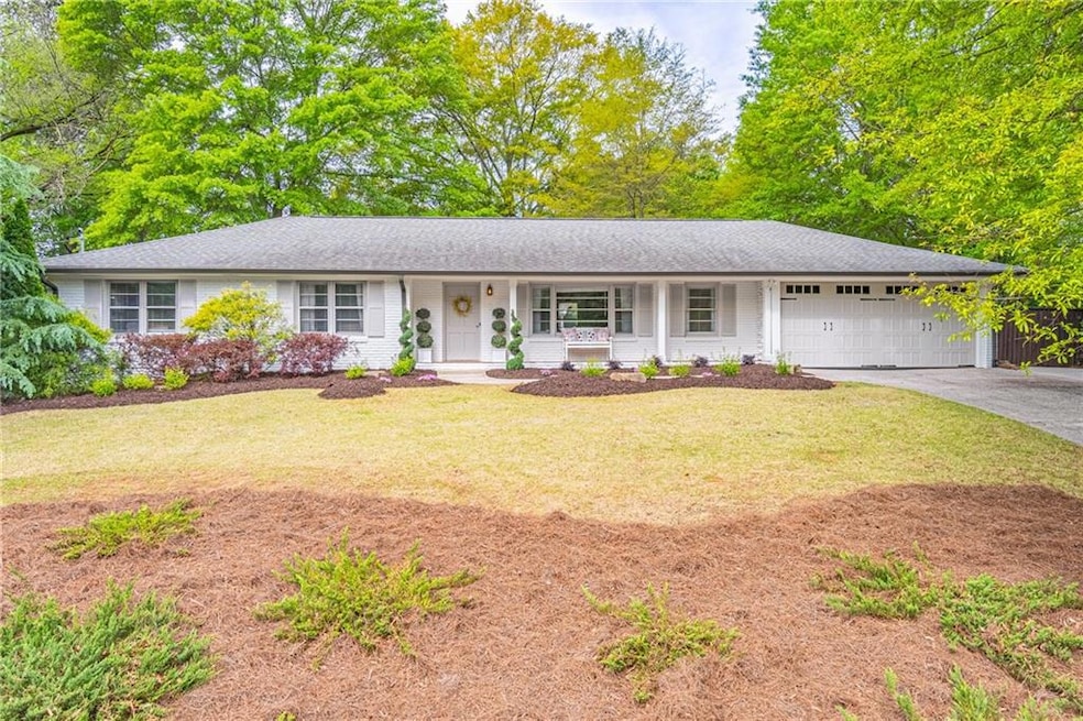 Ranch-style home featuring driveway, a garage, a porch, and a front yard