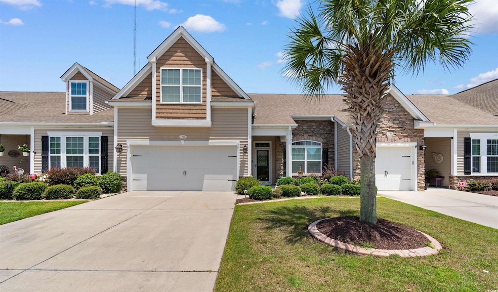 View of front of house featuring driveway, a front yard, stone siding, and a shingled roof