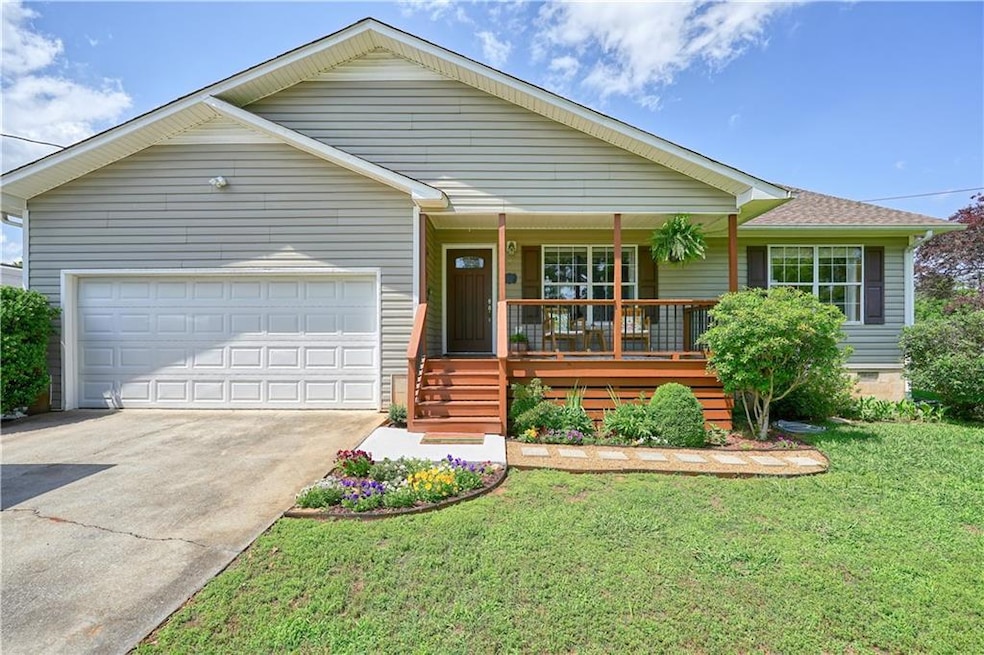 Ranch-style home featuring a porch, driveway, a ga