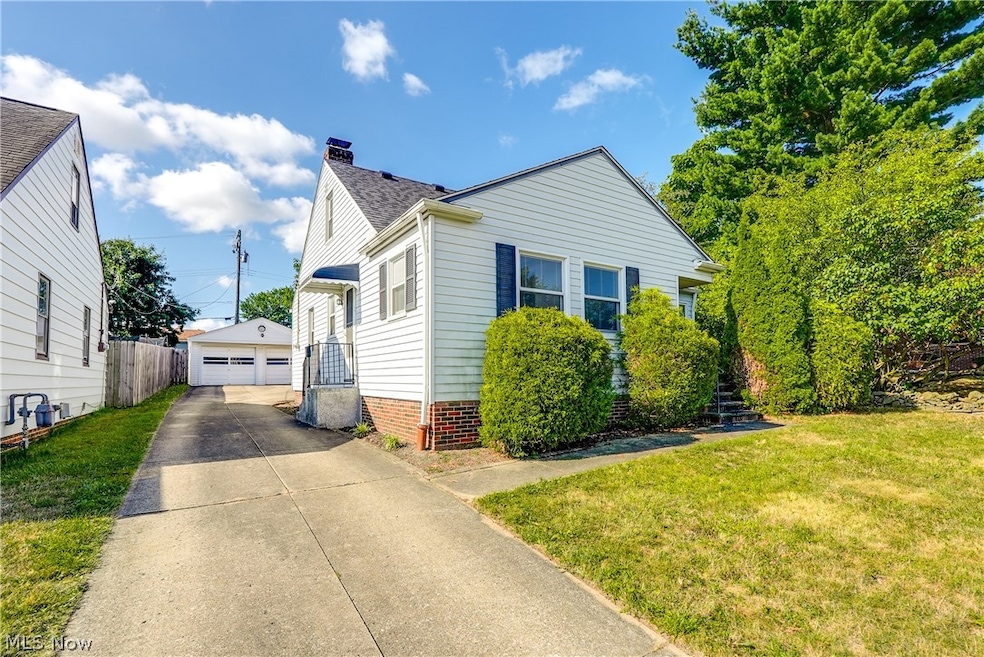 View of front of house featuring a garage, an outdoor structure, and a front yard