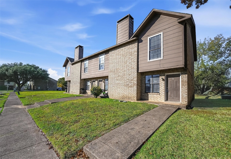 Back of property with brick siding, a chimney, and a lawn