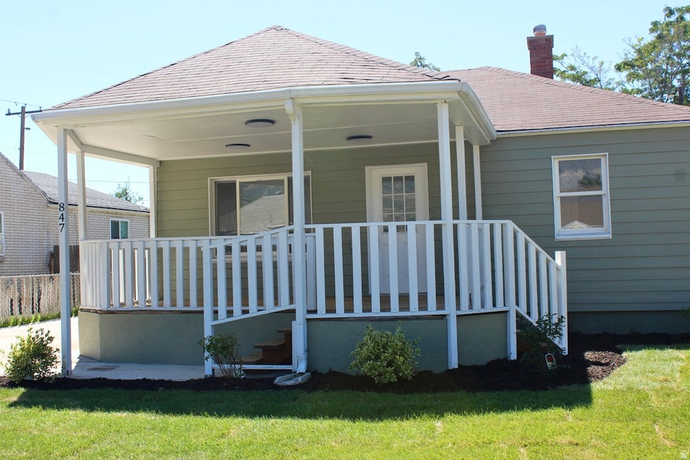Front of house featuring a lawn, a chimney, and a large covered porch.