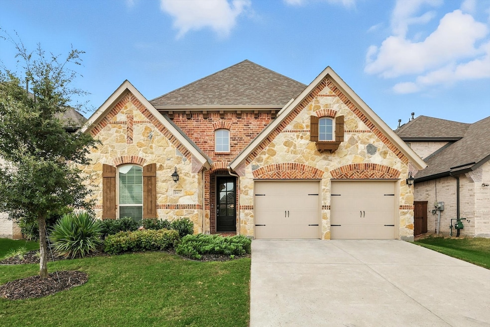 French country inspired facade featuring roof with shingles, stone siding, a front yard, an attached garage, and brick siding