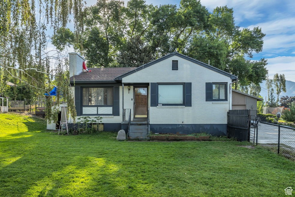View of front of house with entry steps, a chimney, and brick siding