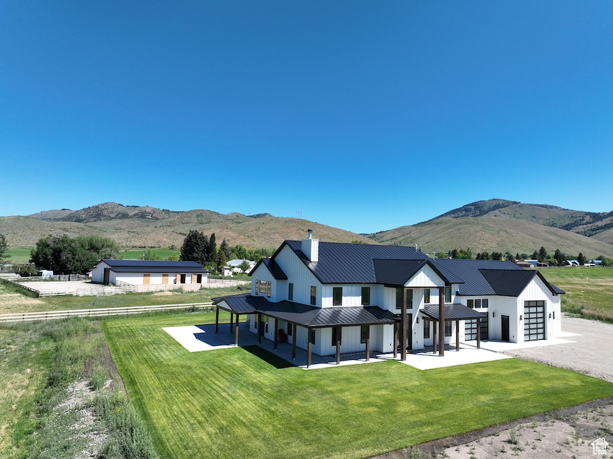 Rear view of house with a mountain view, a chimney, an attached garage, and a lawn