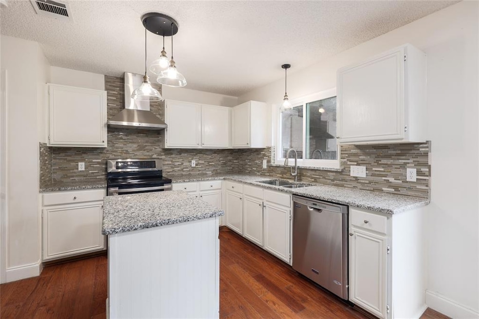 Kitchen with wall chimney range hood, white cabinetry, pendant lighting, dark wood-type flooring, and a textured ceiling