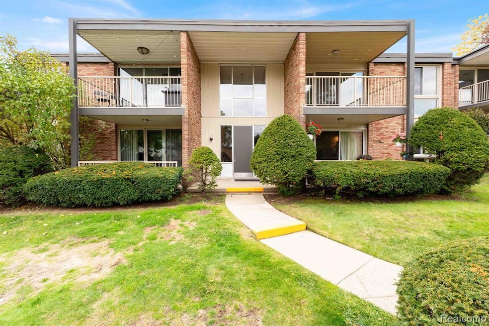 View of front facade featuring brick siding, a front lawn, and a balcony