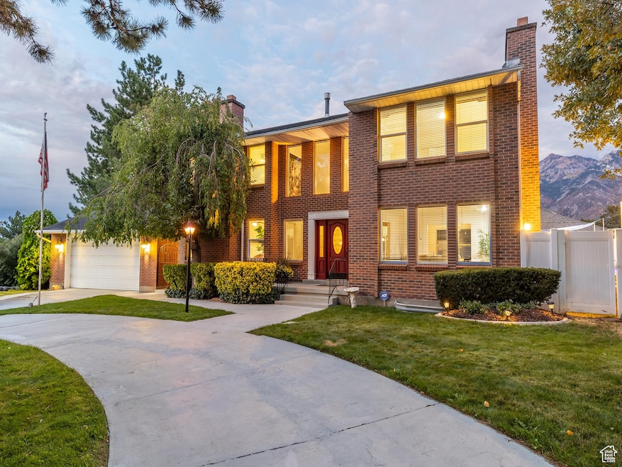View of front of home with a chimney, brick siding, concrete driveway, and an attached garage