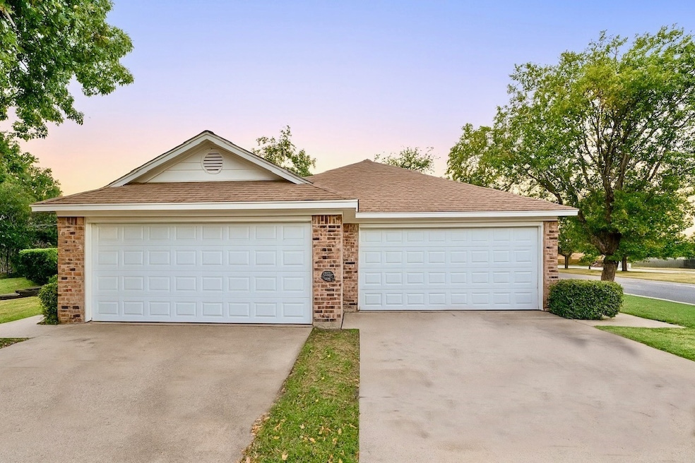Ranch-style home featuring brick siding, roof with shingles, a garage, and concrete driveway