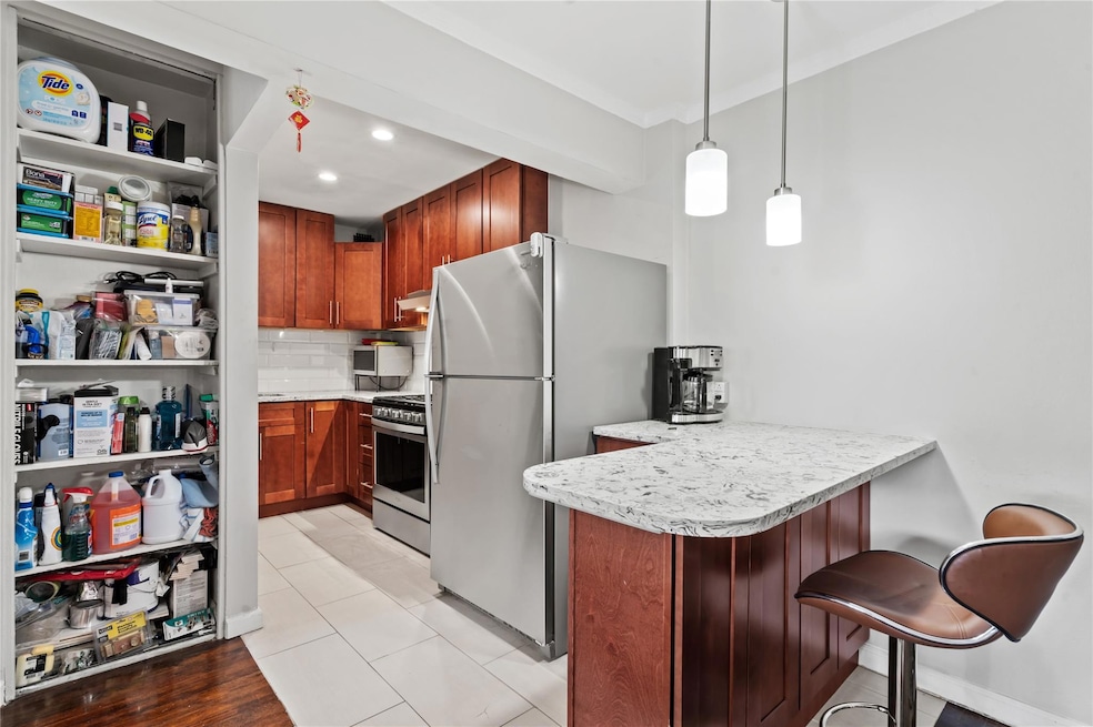 Kitchen featuring stainless steel appliances, a peninsula, light countertops, backsplash, and hanging light fixtures