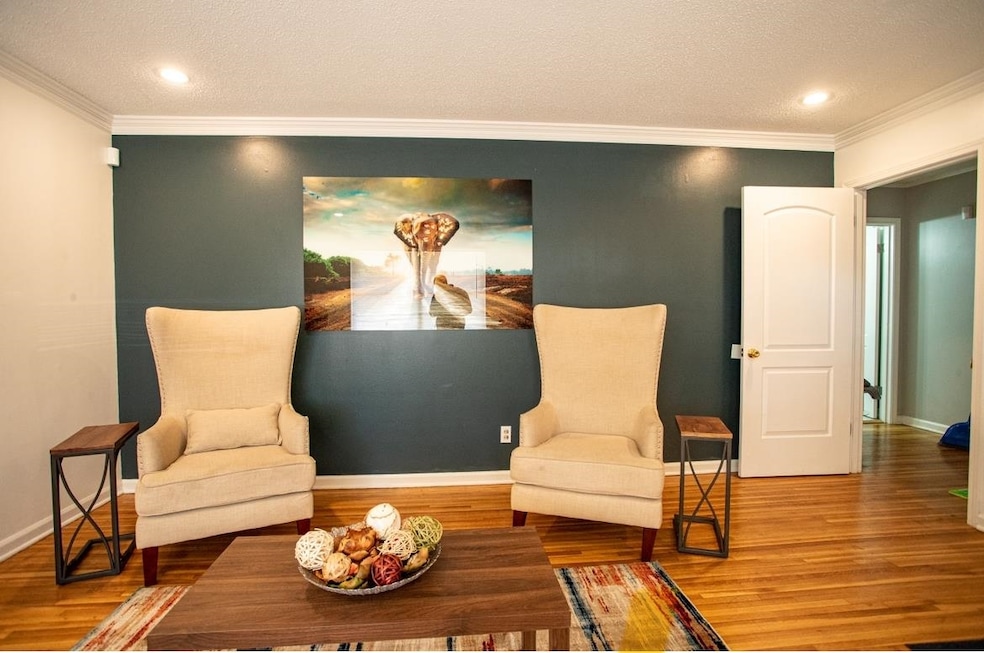 Living area with a textured ceiling, crown molding, recessed lighting, and wood finished floors