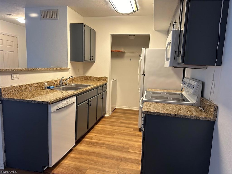 Kitchen featuring light hardwood / wood-style floors, sink, and white appliances