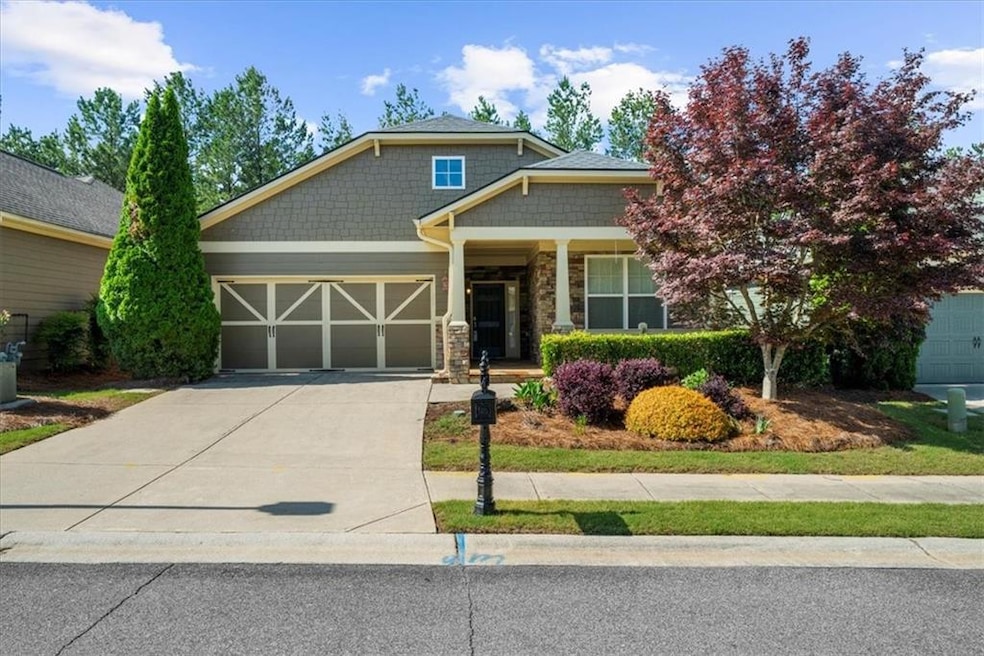 Craftsman-style house featuring stone siding, concrete driveway, an attached garage, and covered porch