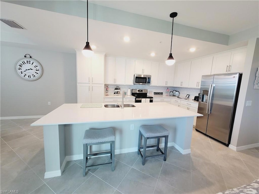 Kitchen featuring sink, appliances with stainless steel finishes, decorative backsplash, and white cabinets