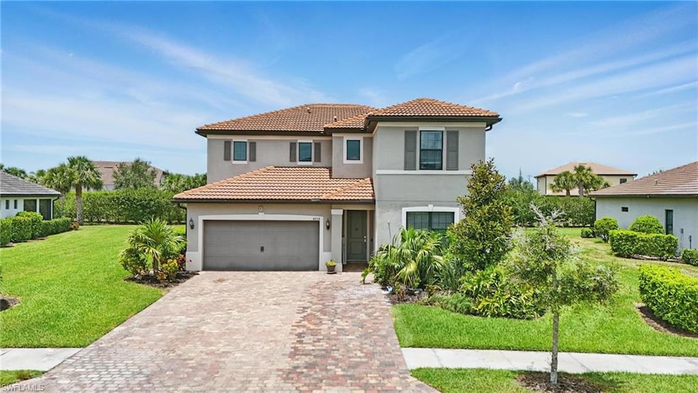 Mediterranean / spanish-style house featuring stucco siding, driveway, a tile roof, and a front yard