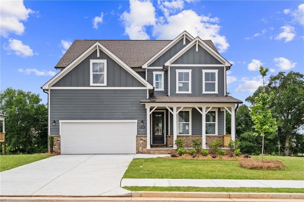 Craftsman-style house featuring a porch, a front yard, a garage, driveway, and brick siding